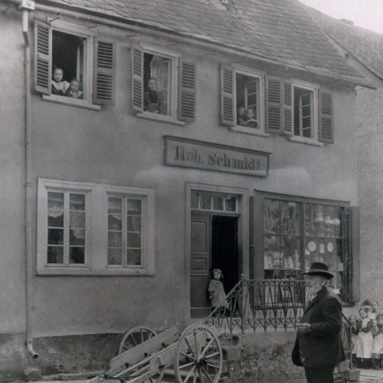 Historisches Gebäude mit Fenster, Personen und einer Kutsche im Vordergrund.