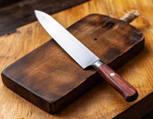 Kochmesser mit Holzgriff auf einem Holzbrett.