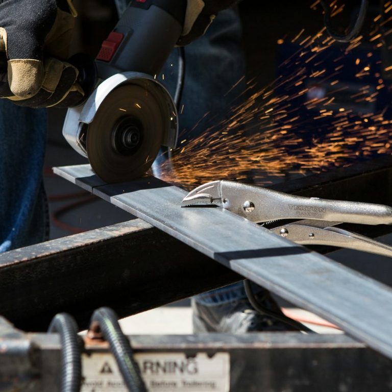 Ein Handwerker schneidet Metall mit einer Winkelschleifmaschine, Funken fliegen.