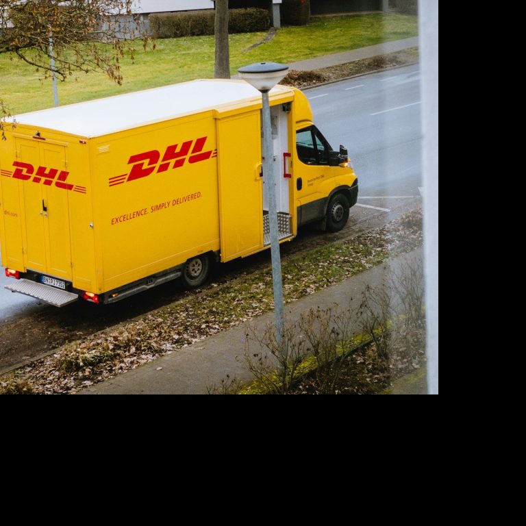 Gelber DHL-Lieferwagen parkt an einer Straße.