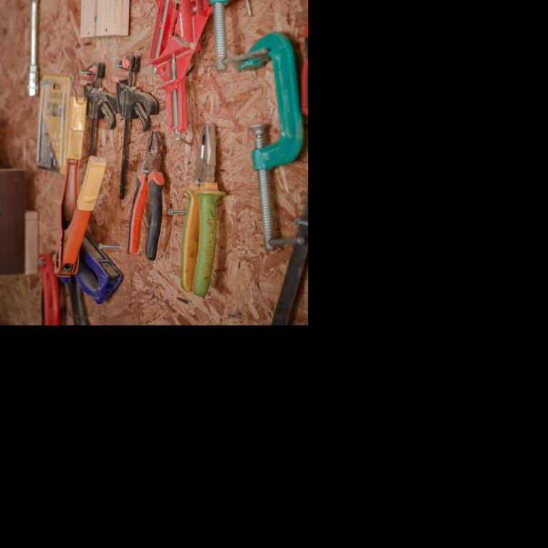 Eine Wand mit verschiedenen Handwerkzeugen, darunter Klemmen in verschiedenen Farben.